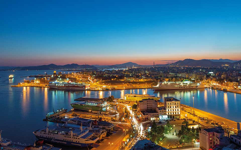 Piraeus ferry port at dusk, with illuminated docks and passenger ships